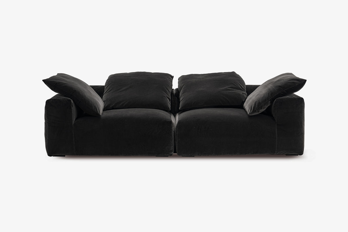 Black velvet two-piece sofa with plush pillow back cushions, studio view