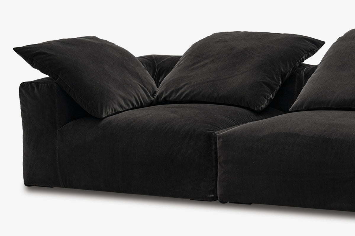Black velvet corner sofa with two angled modules, three-quarter view
