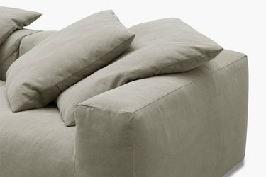 Close-up of sage green sofa cushions and armrest, corner detail