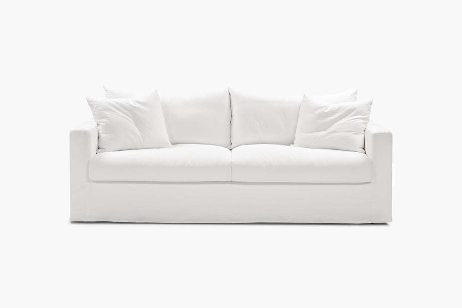 Cream sofa in a living room beside a wooden sideboard and stone bench.