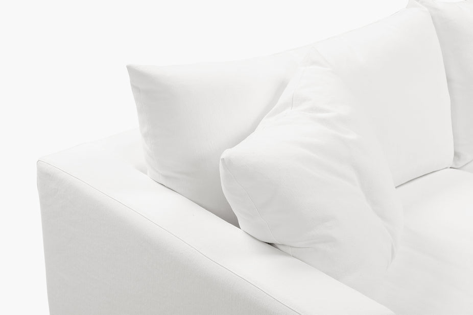 Close-up of a cream sofa arm and cushions photographed from an angle.