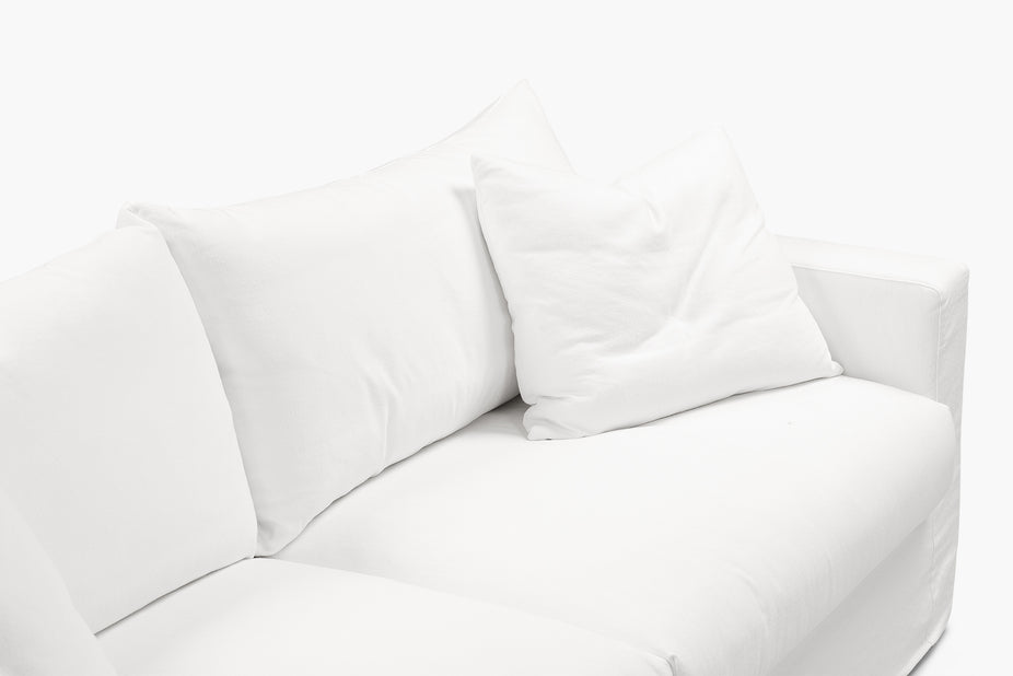 Close-up of a cream sofa back cushions and armrest from a side angle.