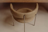 A modern upholstered accent chair with a curved backrest and seat, upholstered in a warm taupe-brown suede-like material, supported by slim metallic legs, shown in a minimalist interior setting.