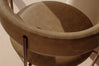 Close-up of a modern upholstered chair with a curved backrest and seat, upholstered in taupe-brown leather or faux leather, featuring visible stitching and dark metal legs.