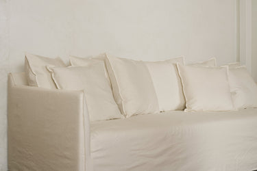 Cream sofa with five back cushions, studio front view against plain wall