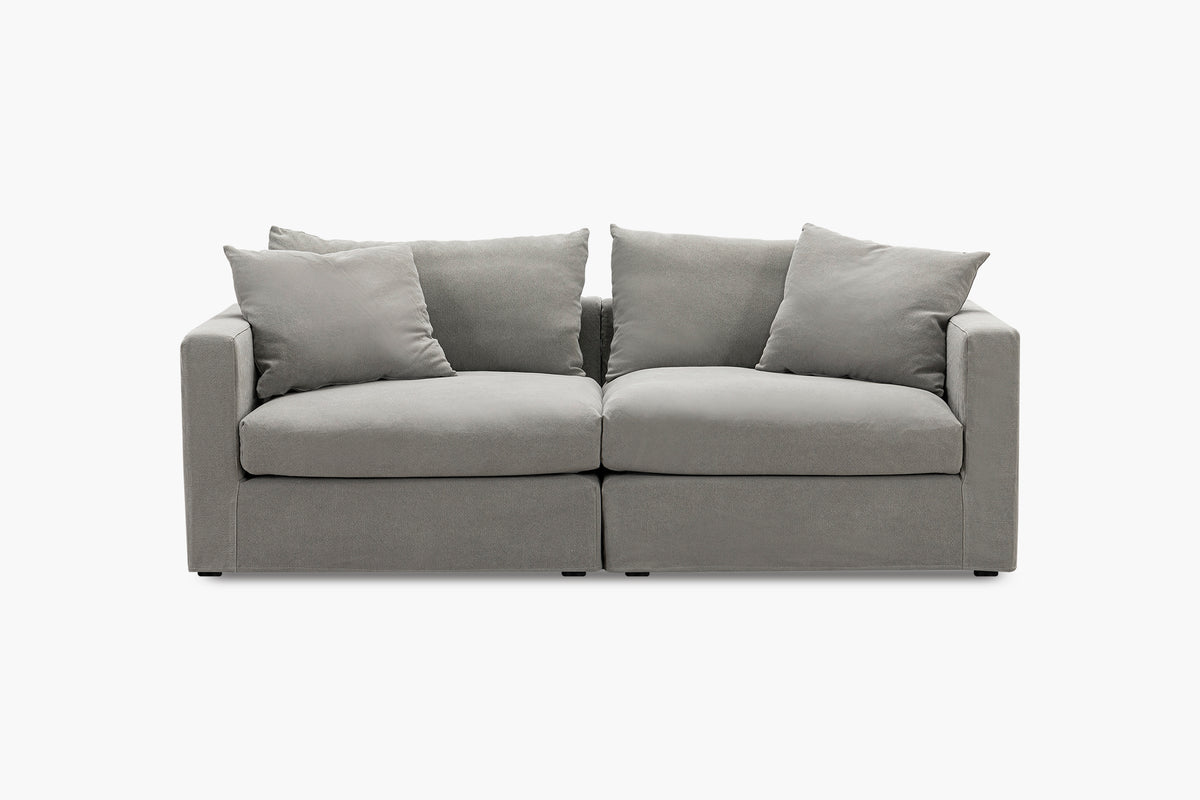 Light grey two-seat sofa with four back cushions, studio front view