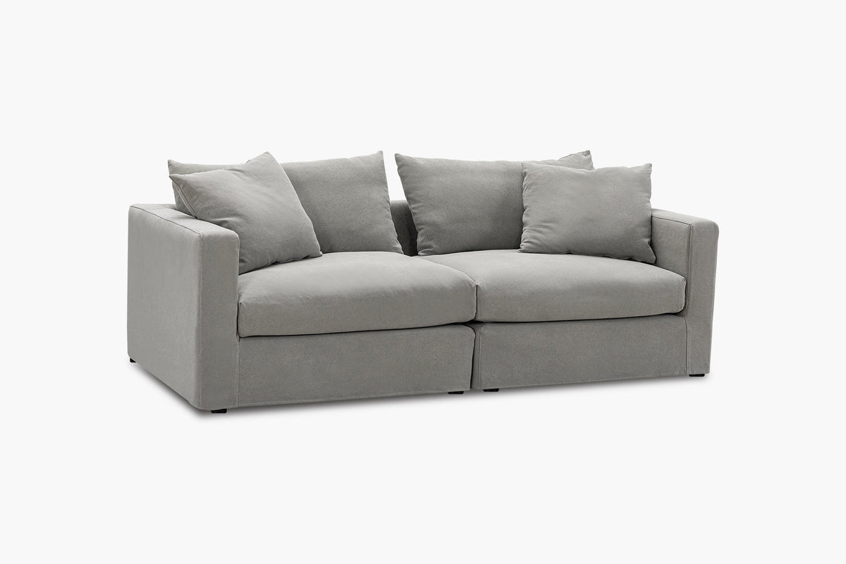 Light grey two-seat sofa with four back cushions, studio side-angled view