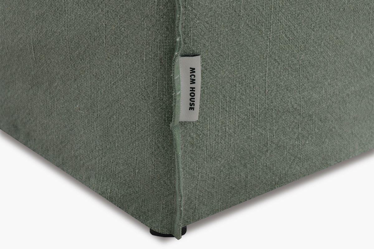 Corner of a textured green fabric product with a brand label on a white background