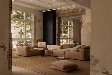 Beige corner sofa in a rustic loft with floor cushions and a lamp