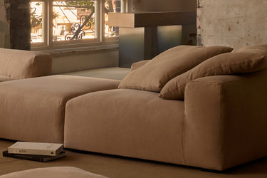 Close-up of caramel corner sofa in a loft with warm evening light