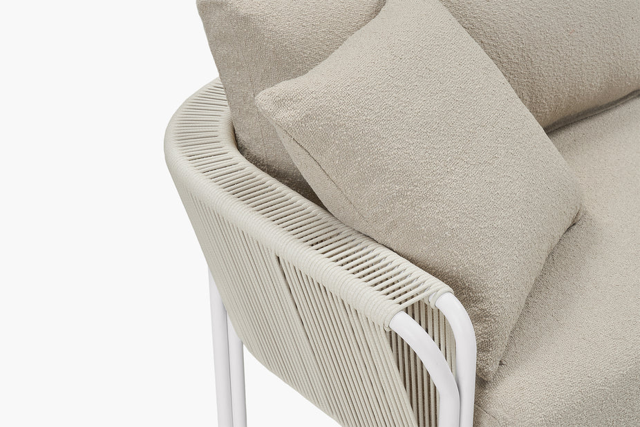 Close-up corner of white rope armrest and beige boucle cushions