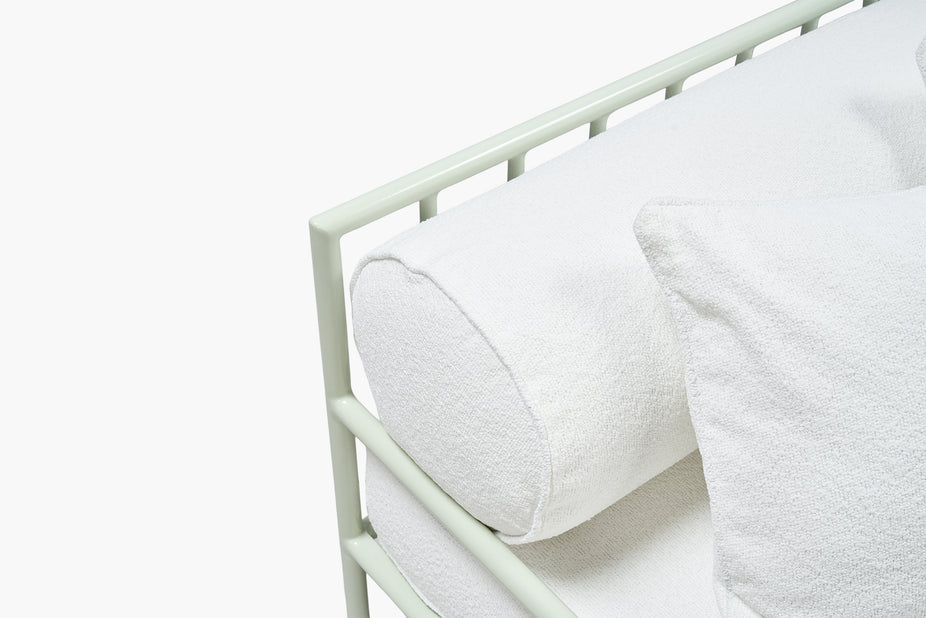 Close-up corner of white boucle cushion and sage green frame edge