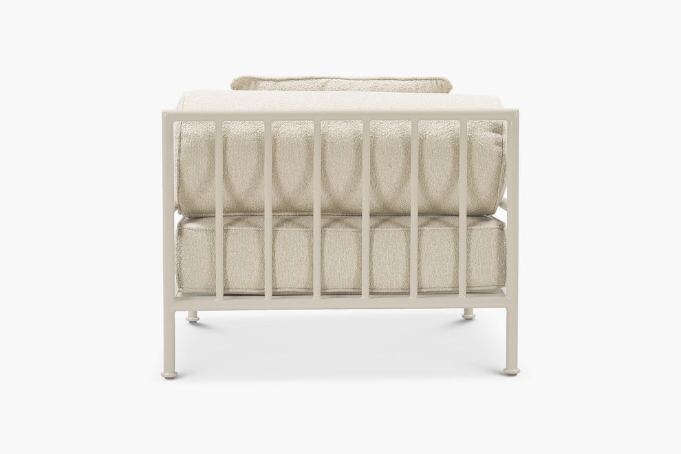 Cream boucle outdoor lounge chair with a glossy tan frame, rear view