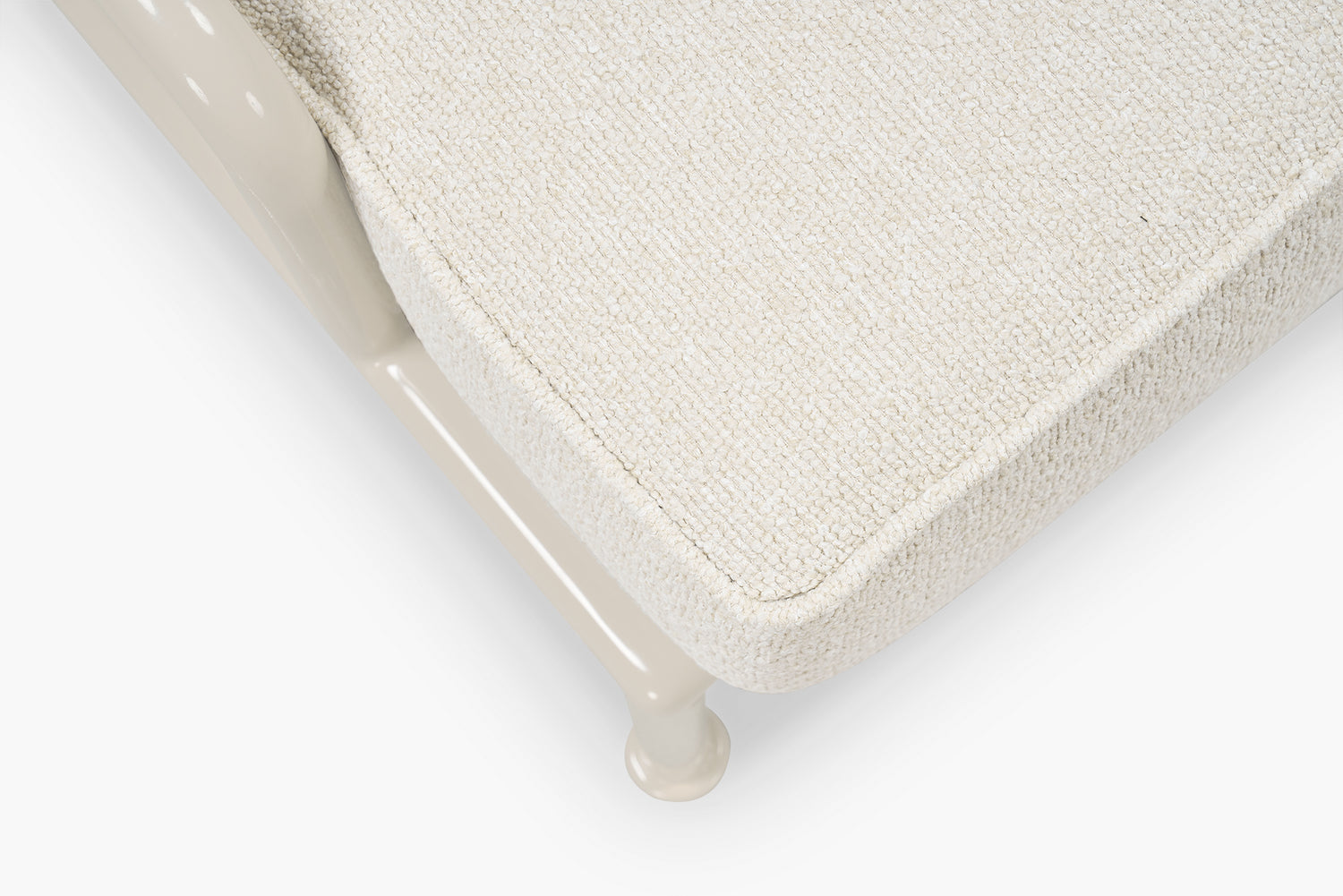Close-up corner of cream boucle cushion and glossy tan frame leg on a lounge chair
