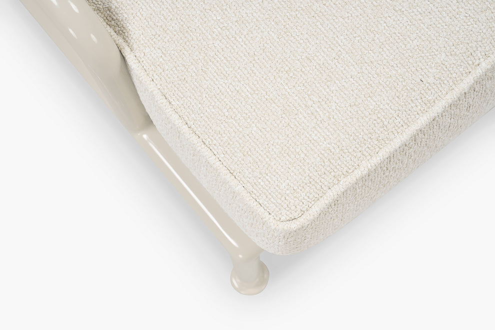 Close-up corner of cream boucle cushion and glossy tan frame leg on a lounge chair