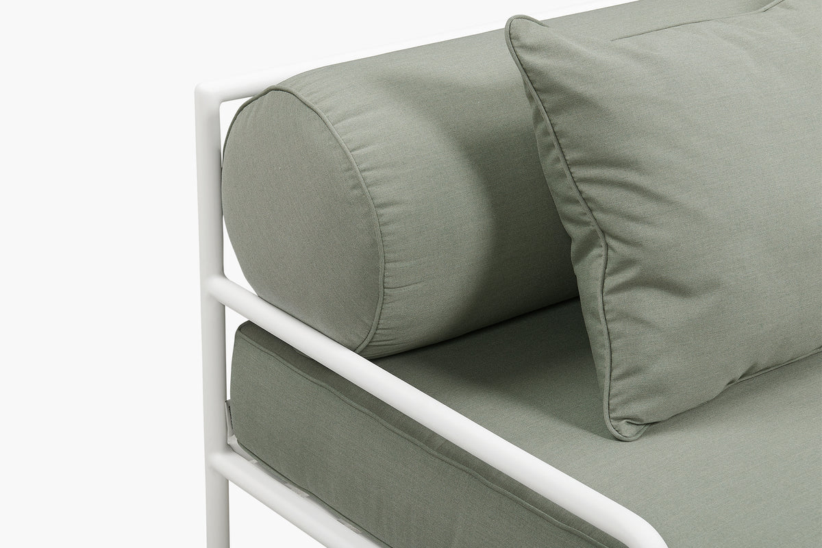 Close-up studio shot of sage green cushions on a white sofa frame
