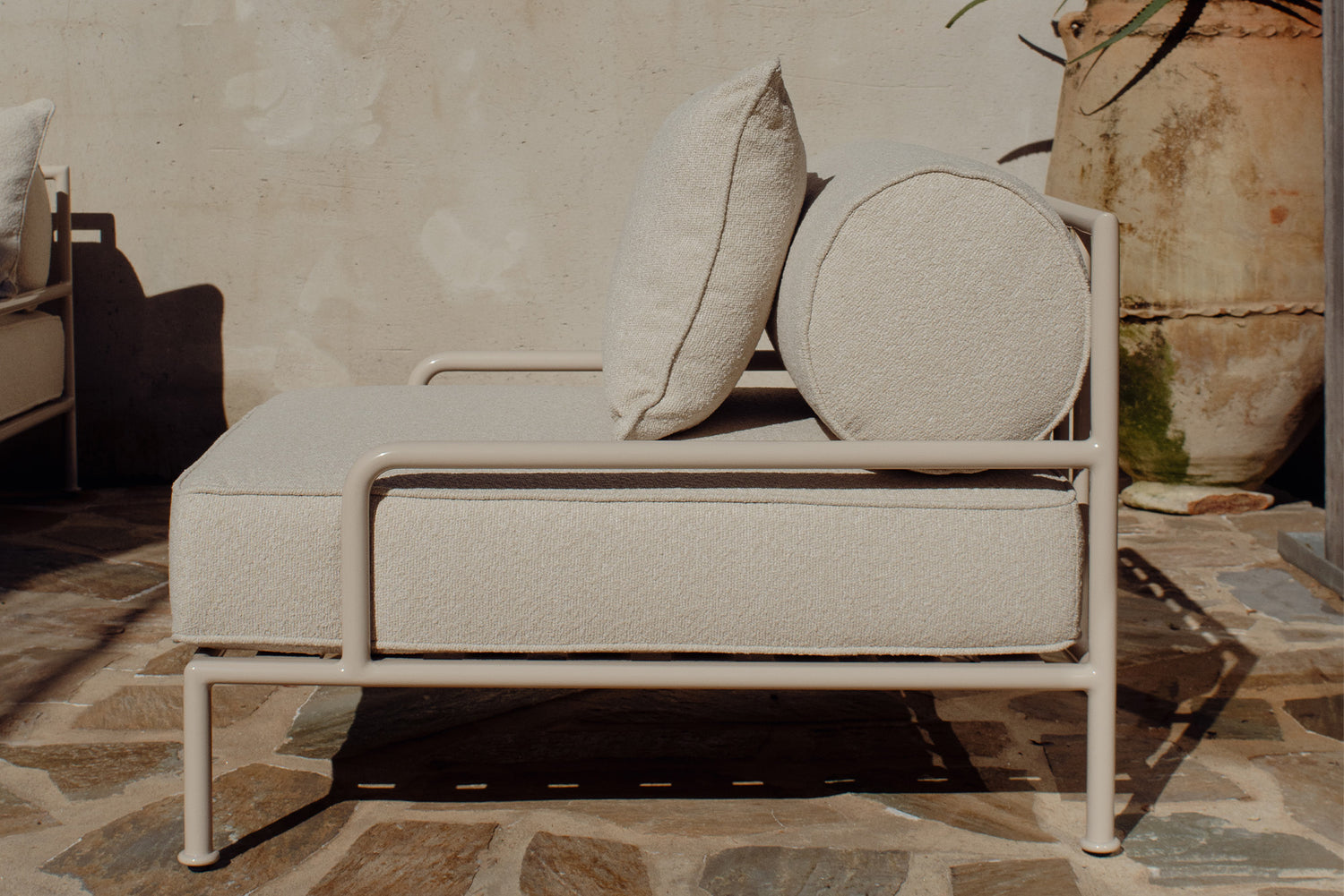 Cream boucle lounge chair beside a large terracotta urn on patio