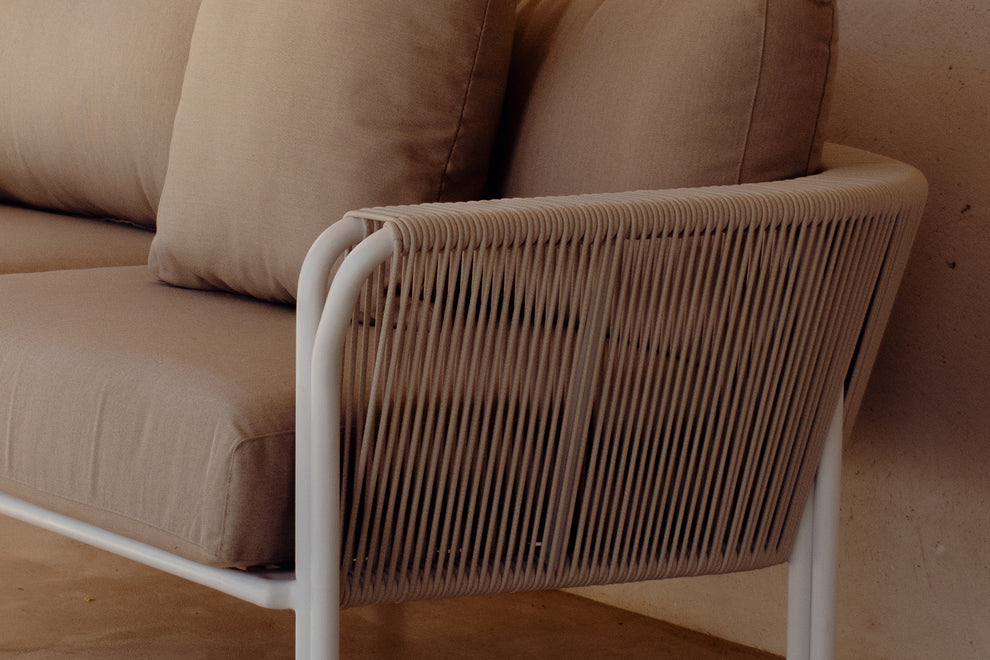 Close-up of white rope armrest and beige linen cushions on patio
