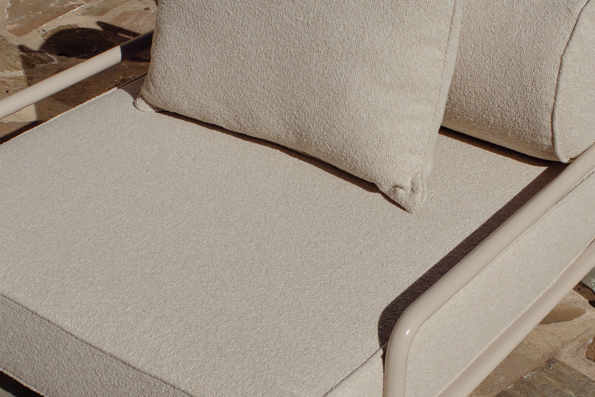 Close-up of cream boucle cushion and glossy tan frame corner on a lounge chair