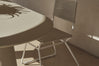 Rope dining chair at a table beside a sunlit stone wall