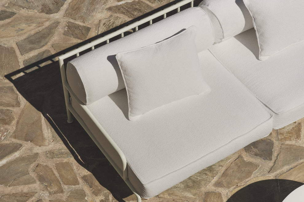 Close-up of white boucle cushions and slatted frame on stone patio