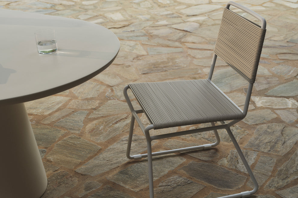 Cream rope outdoor dining chair beside a round table, patio