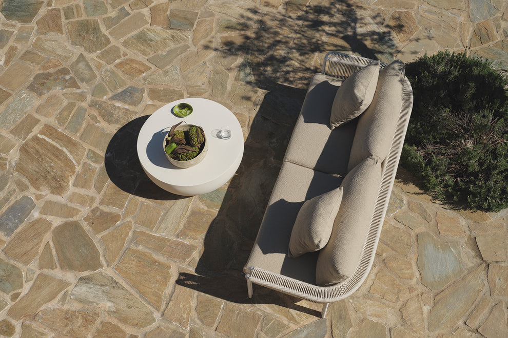Overhead view of beige sofa and round table on stone patio