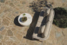 Overhead view of beige sofa and round table on stone patio