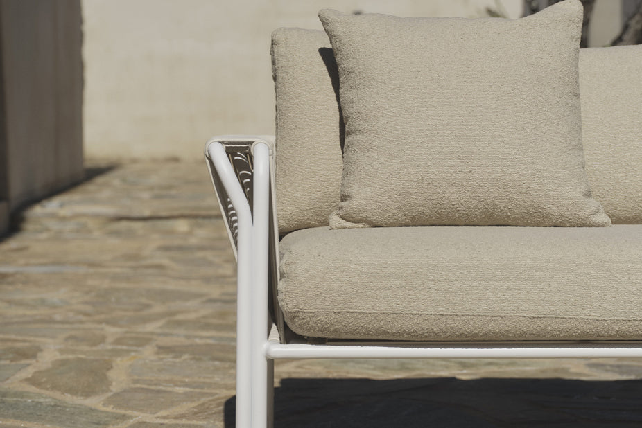 Close-up of white rope armrest and beige boucle cushions on patio