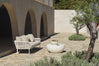 Beige boucle sofa under a stone archway beside an olive tree