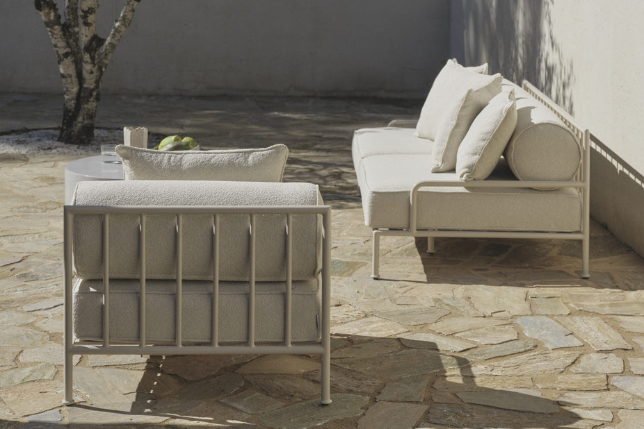 Lounge chair and sofa on stone patio beside a tree and table