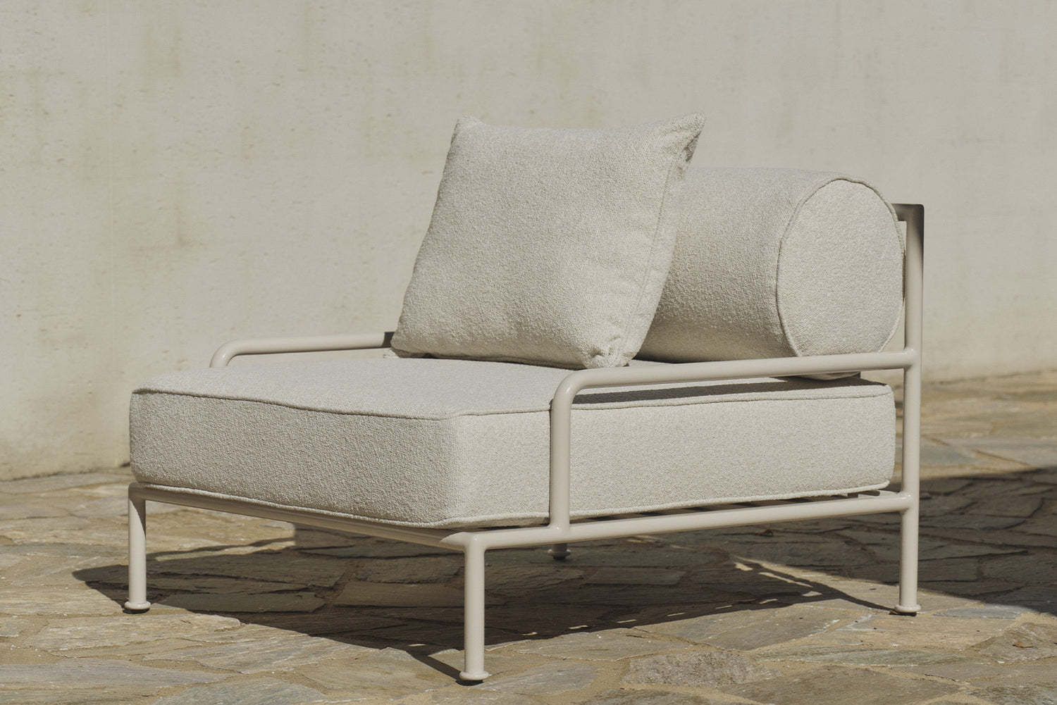 Cream boucle outdoor lounge chair with slatted frame on stone patio