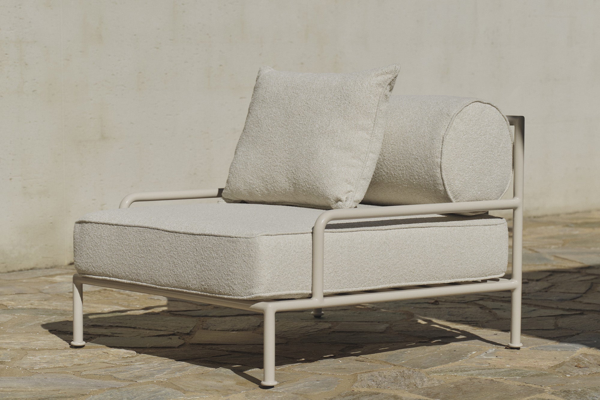 Cream boucle outdoor lounge chair with slatted frame on stone patio