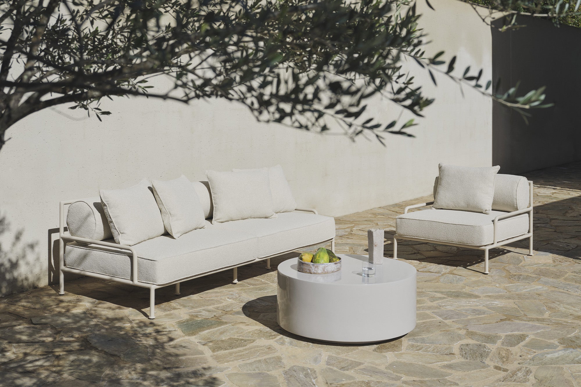 White boucle sofa and chair with coffee table under an olive tree