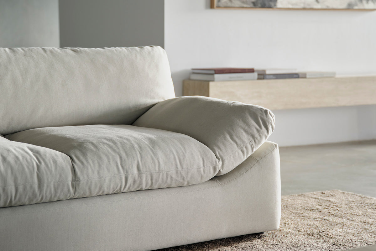 Close-up of a cream sofa arm and cushion beside a wooden console table.