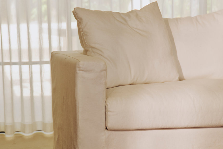 Cream two-seater sofa shown from the front with matching cushions in a studio.