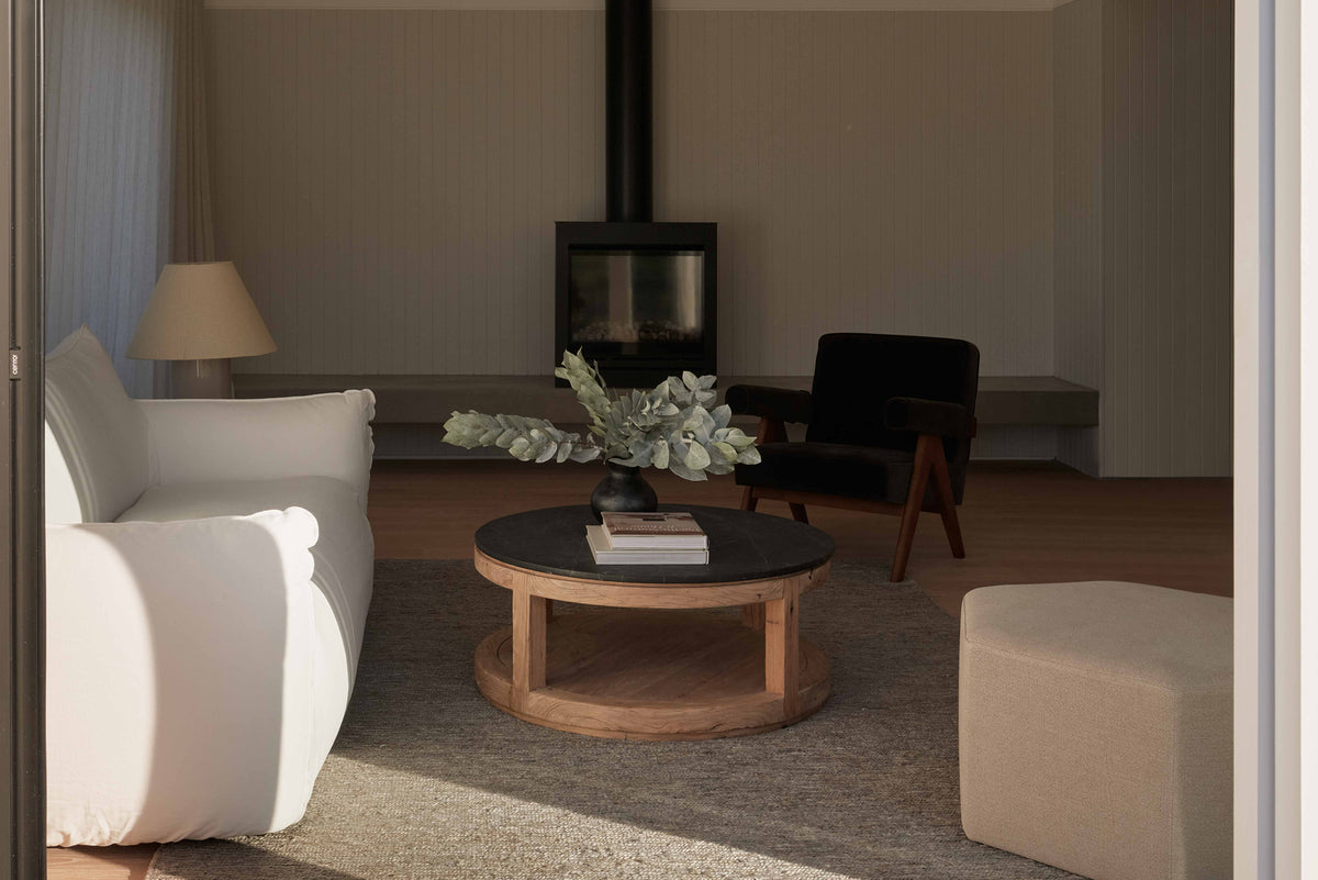 A round coffee table made of black stone and old elm timber