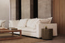 White sofa with plush cushions in a living room with concrete walls and a wood coffee table.
