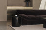 Close-up of a dark brown velvet sofa beside a glossy black side table.