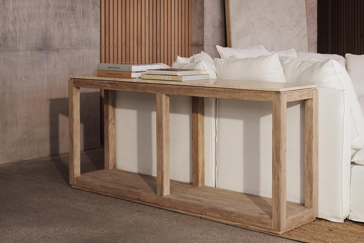 A natural stone and old elm timber console table in a room with a white sofa, placed against a neutral backdrop.