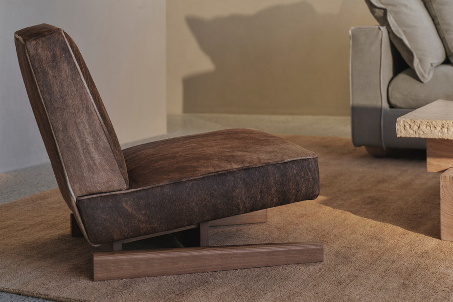 Brown upholstered chair in a living room setting with a neutral color palette.