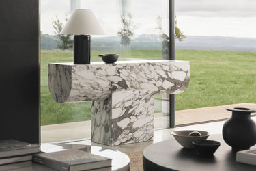 Marble console table in a modern living room with large windows.