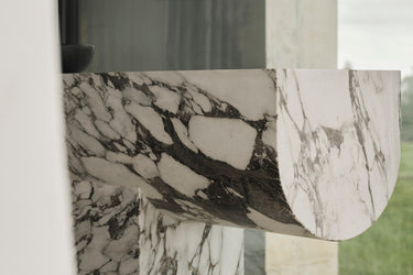 A luxurious white marble console table with grey veining, featuring a bold new material language with clean geometry and soft edges.