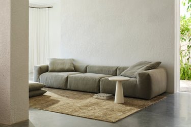 Sage green sofa in a bright room with a round white side table