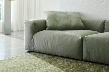 Sage green sofa in a bright room with sheer curtains and a patterned rug