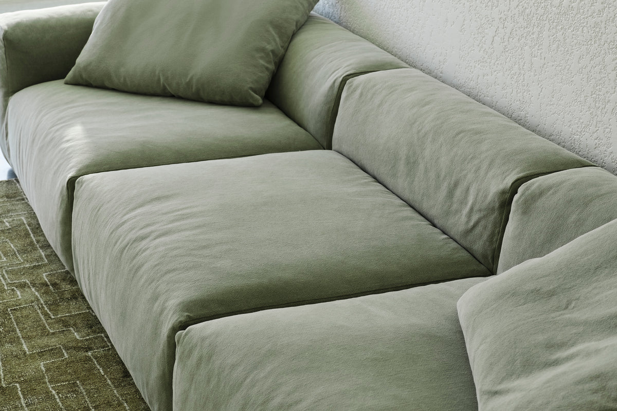 Close-up of sage green sofa cushions on a patterned area rug