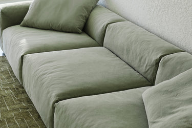 Close-up of sage green sofa cushions on a patterned area rug
