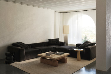 Black velvet corner sectional sofa in a bright room with an arched window