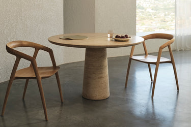 Round wooden table with two matching chairs in a minimalistic room.
