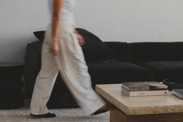 Black velvet sofa in a living room with a person walking past